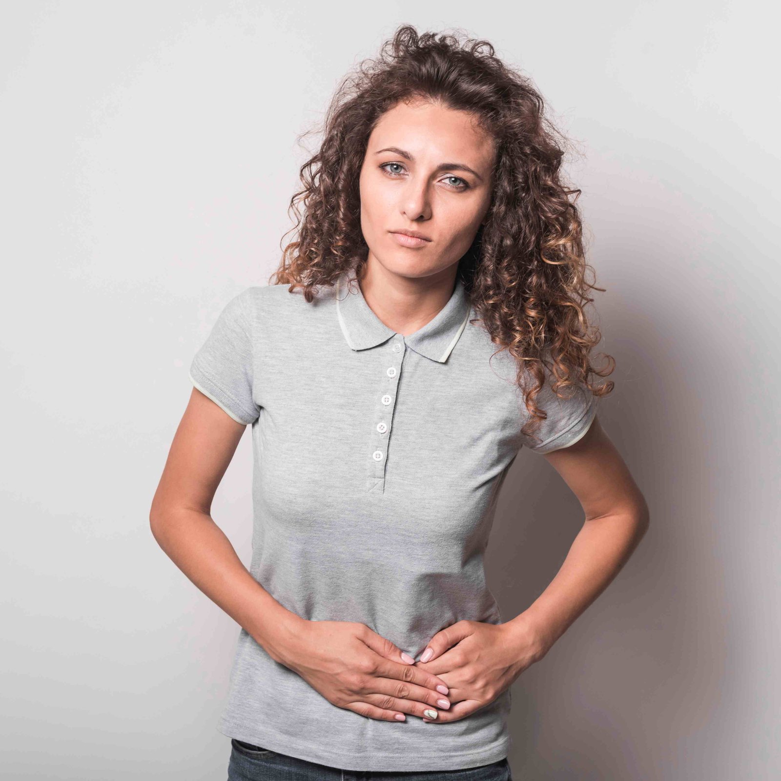 close up young woman suffering from stomach ache against gray background 11zon