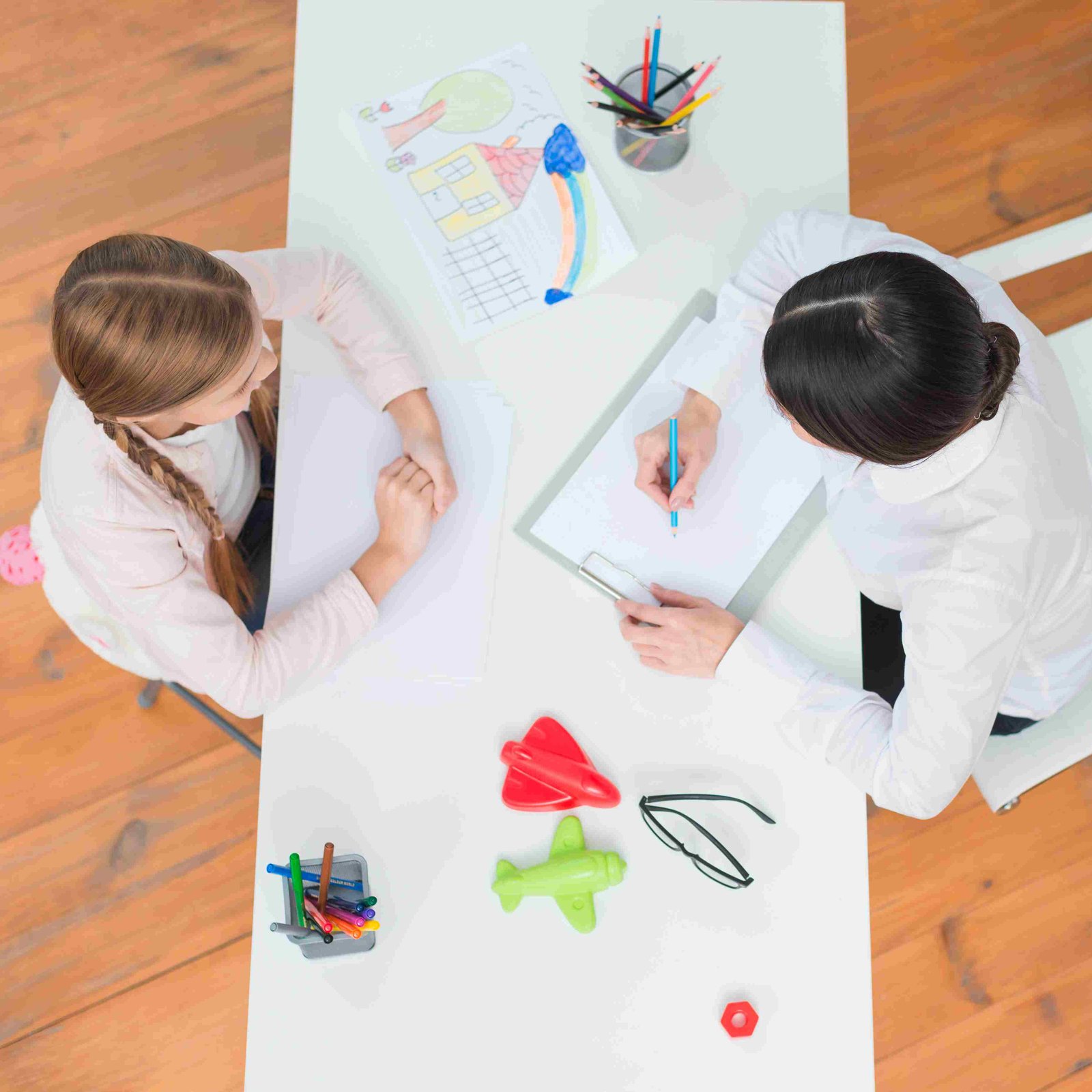 elevated view little girl talking with her female psychologist taking note clipboard 11zon